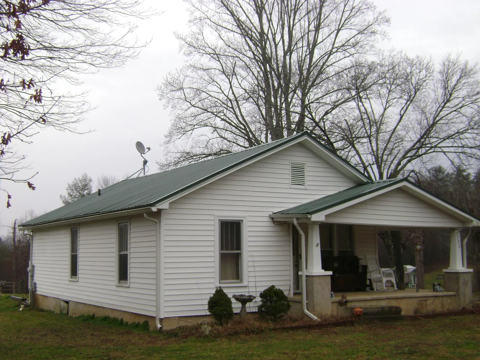 Green metal roof on a white bungalow with a side porch in Carlisle