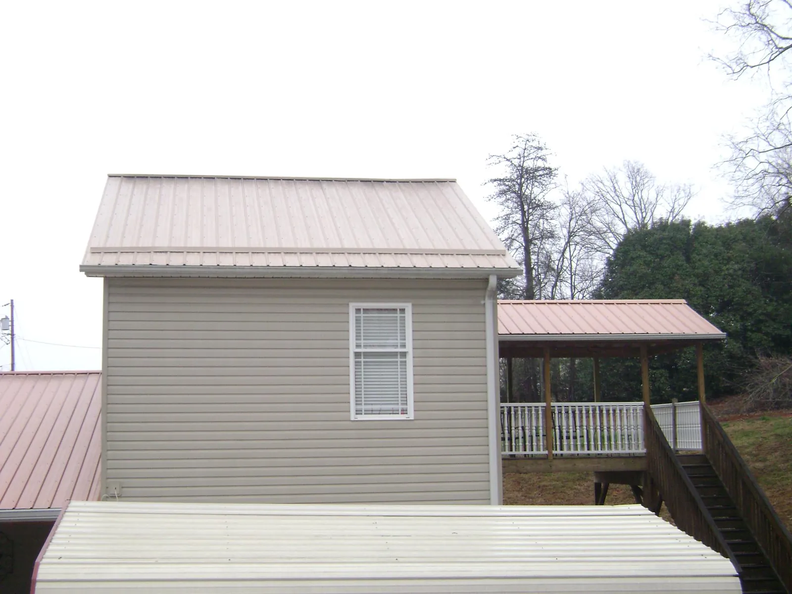 Tan metal roofs on a two story addition and attached porch, from a Roof Replacement job in Carlisle